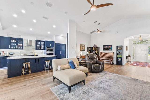 living room with sink, vaulted ceiling, and light wood-type flooring