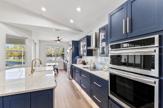 kitchen with sink, blue cabinetry, appliances with stainless steel finishes, and vaulted ceiling