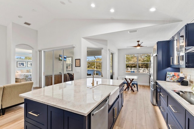 kitchen featuring sink, vaulted ceiling, ceiling fan, an island with sink, and appliances with stainless steel finishes