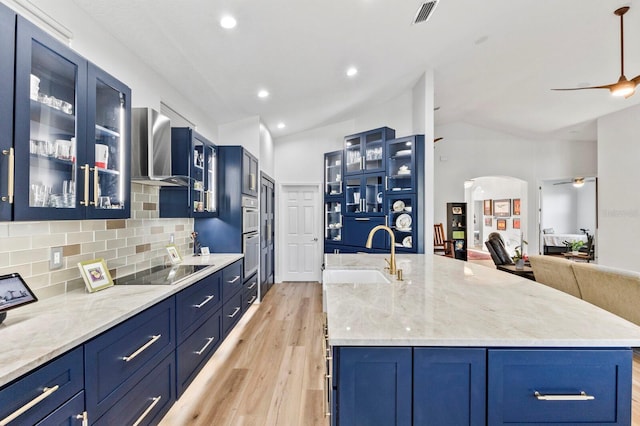 kitchen with blue cabinetry, ceiling fan, sink, an island with sink, and black electric cooktop