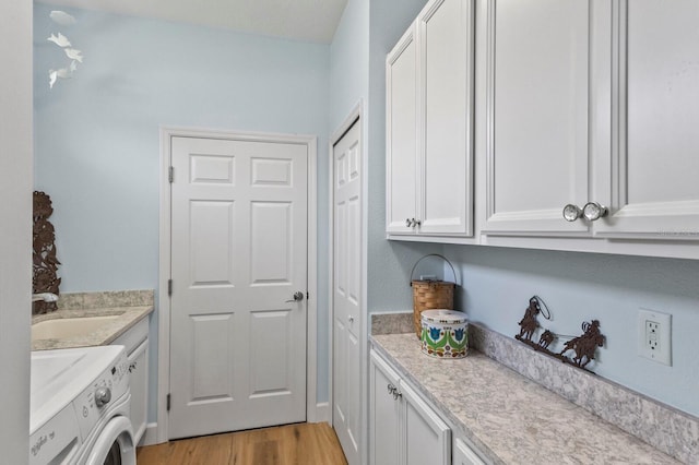 clothes washing area with light hardwood / wood-style floors, cabinets, sink, and washing machine and dryer