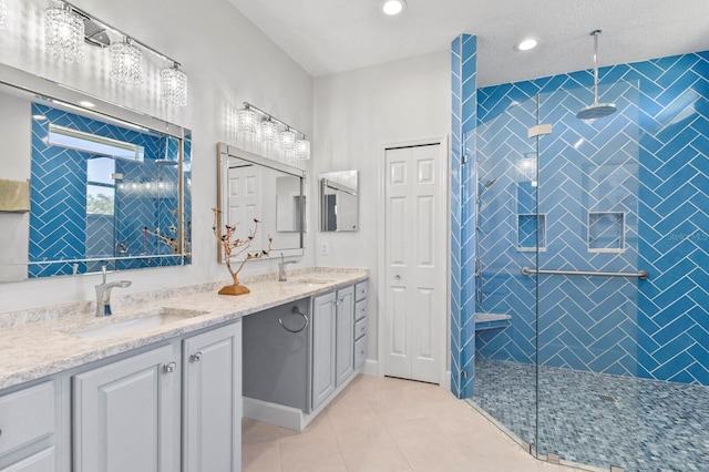 bathroom with tile patterned flooring, vanity, and tiled shower