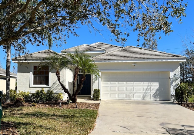 single story home featuring a tiled roof, a garage, concrete driveway, and stucco siding