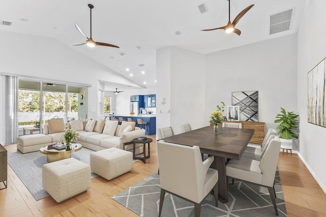 dining space featuring ceiling fan, high vaulted ceiling, and light wood-type flooring