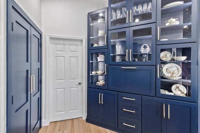 bar with blue cabinetry and light hardwood / wood-style floors