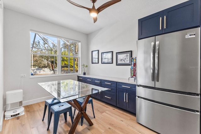 kitchen featuring blue cabinetry, stainless steel refrigerator, ceiling fan, and light wood-type flooring