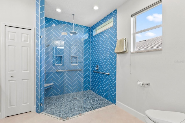 bathroom featuring tile patterned flooring, toilet, and tiled shower