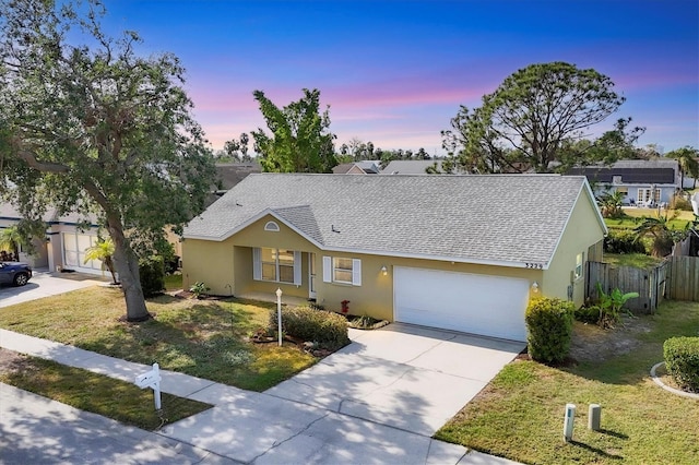 ranch-style house featuring driveway, fence, a lawn, and stucco siding