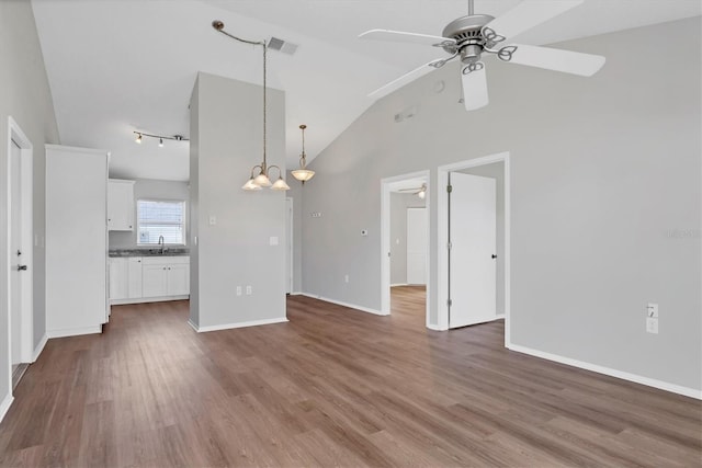 unfurnished living room featuring hardwood / wood-style floors, ceiling fan with notable chandelier, high vaulted ceiling, and sink