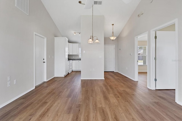 unfurnished living room featuring a chandelier, wood-type flooring, and high vaulted ceiling