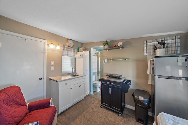 kitchen with white cabinets, carpet, sink, and stainless steel refrigerator