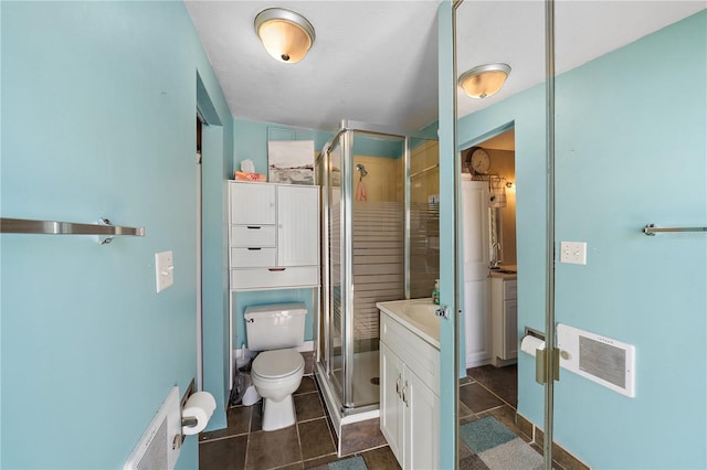 bathroom featuring vanity, toilet, and a shower with shower door