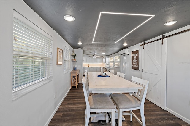 dining room with a textured ceiling, ceiling fan, dark wood-type flooring, a barn door, and an AC wall unit