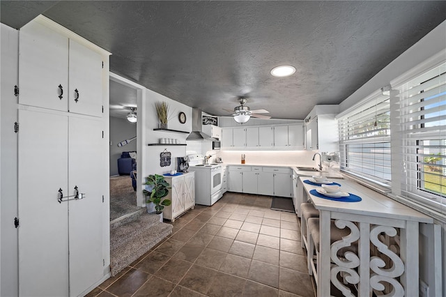 kitchen featuring white cabinetry, sink, ceiling fan, white electric range oven, and dark tile patterned floors