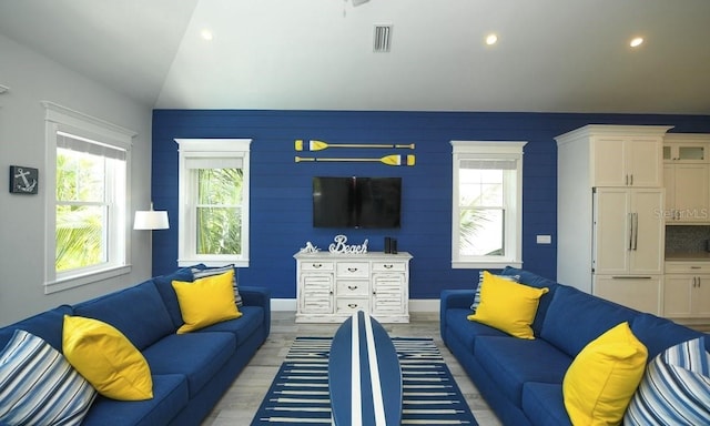 living room featuring lofted ceiling and light hardwood / wood-style floors