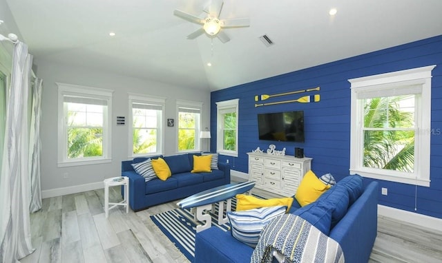 living room featuring ceiling fan, vaulted ceiling, a healthy amount of sunlight, and light wood-type flooring