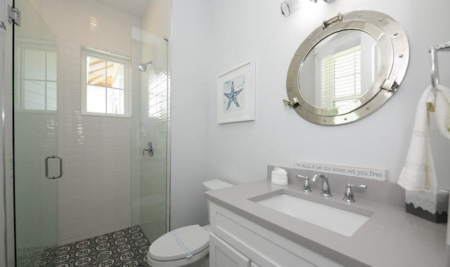 bathroom featuring vanity, a shower with shower door, and toilet