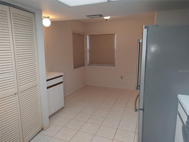 kitchen featuring white cabinetry, light tile patterned floors, and stainless steel refrigerator