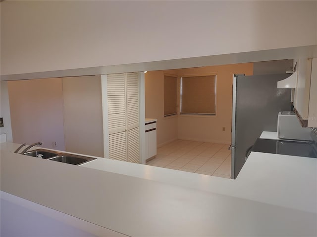 kitchen featuring sink, kitchen peninsula, stove, extractor fan, and light tile patterned floors