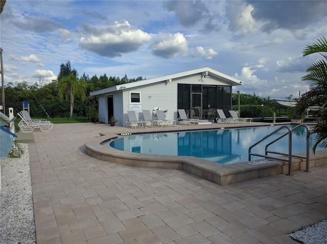 view of swimming pool with a sunroom and a patio area