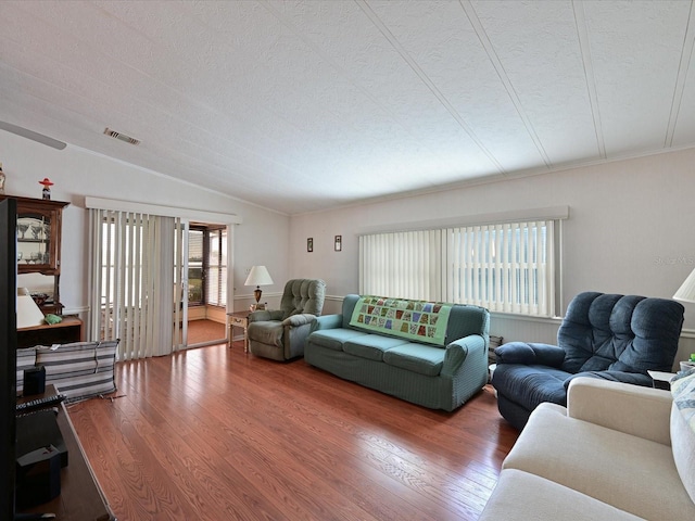 living room with a textured ceiling, wood-type flooring, and vaulted ceiling