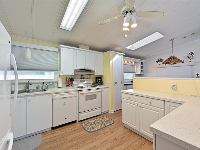 kitchen with a skylight, white appliances, decorative light fixtures, light hardwood / wood-style floors, and white cabinetry