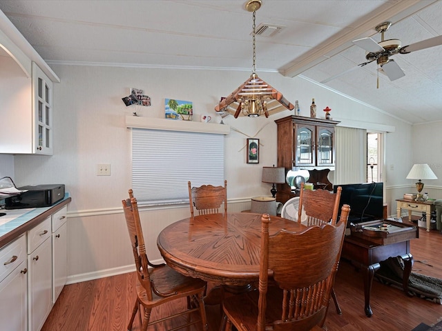 dining area with ceiling fan, lofted ceiling with beams, and hardwood / wood-style flooring