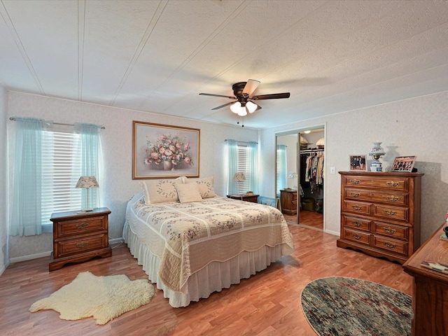 bedroom with ceiling fan, hardwood / wood-style floors, a textured ceiling, a walk in closet, and a closet