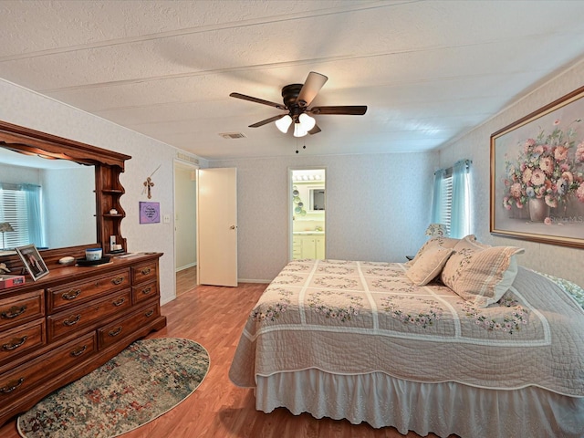 bedroom with ceiling fan, light hardwood / wood-style floors, and ensuite bathroom