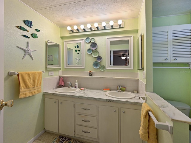 bathroom with backsplash, vanity, a textured ceiling, and tile patterned flooring