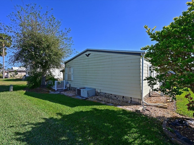 view of side of home featuring a lawn and central AC unit