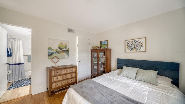 bedroom with hardwood / wood-style flooring and ensuite bathroom