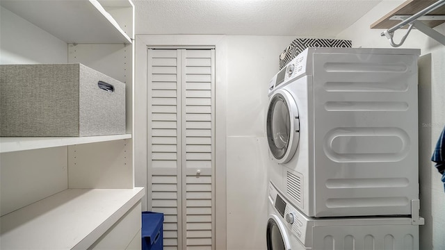 laundry room featuring stacked washer / drying machine and a textured ceiling