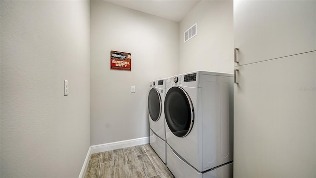 washroom with washer and clothes dryer and cabinets