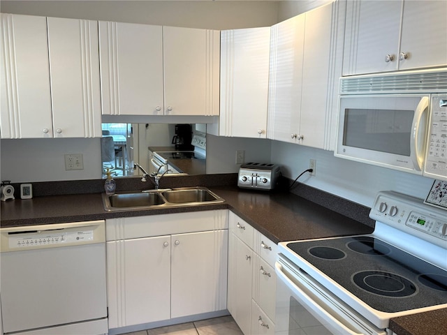 kitchen featuring white cabinetry, sink, light tile patterned floors, and white appliances