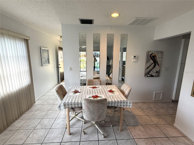 dining space with light tile patterned flooring and a textured ceiling