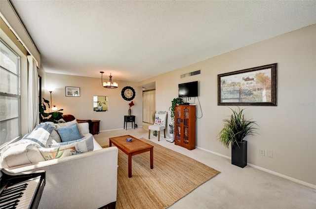 living room featuring a chandelier, light carpet, and a textured ceiling