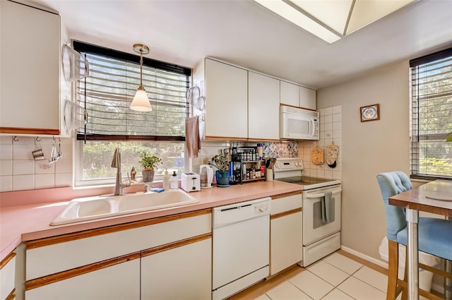 kitchen featuring white appliances, sink, decorative light fixtures, white cabinets, and light tile patterned flooring