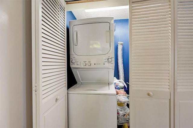 laundry room featuring stacked washing maching and dryer and a textured ceiling