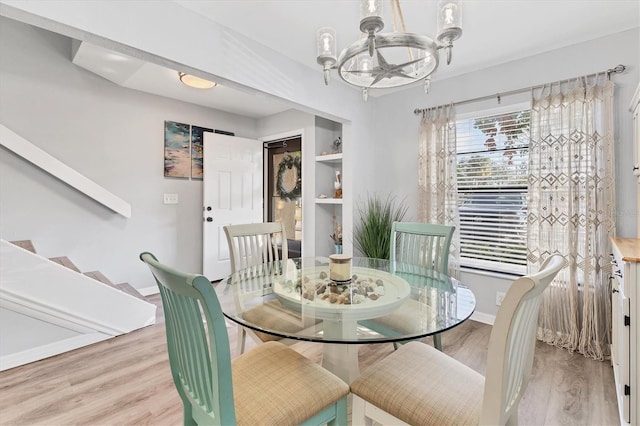 dining space with light hardwood / wood-style flooring and a notable chandelier