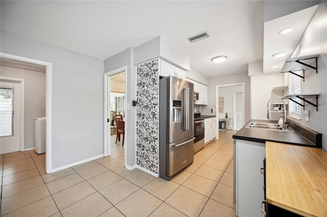 kitchen with sink, stainless steel appliances, white cabinets, washer / dryer, and light tile patterned flooring