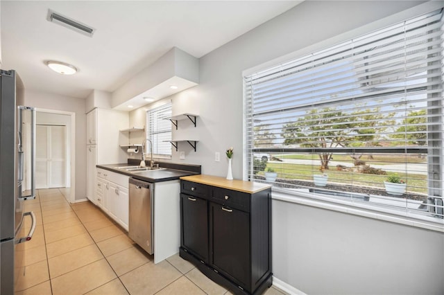 kitchen featuring white cabinetry, sink, light tile patterned floors, and stainless steel appliances