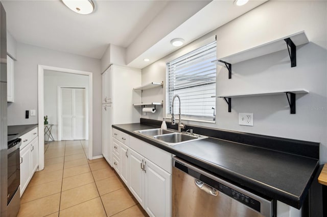 kitchen featuring stove, stainless steel dishwasher, sink, white cabinets, and light tile patterned flooring