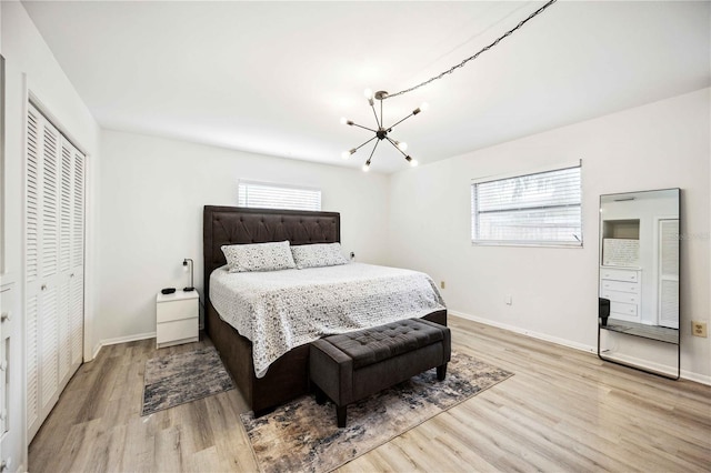 bedroom with a closet, light wood-type flooring, and an inviting chandelier