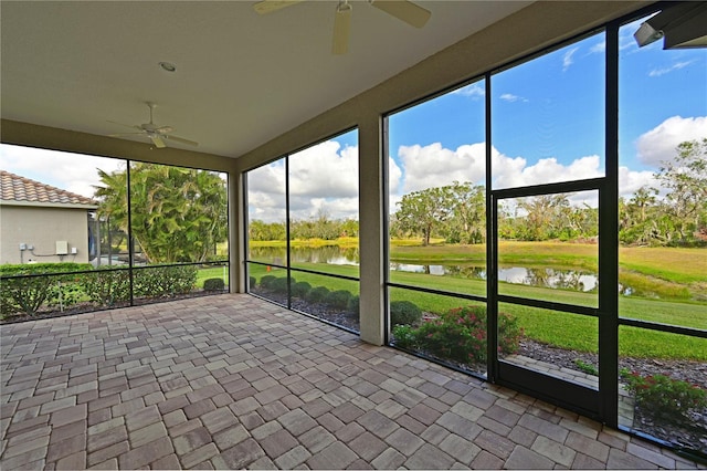 unfurnished sunroom featuring a water view, ceiling fan, and a wealth of natural light