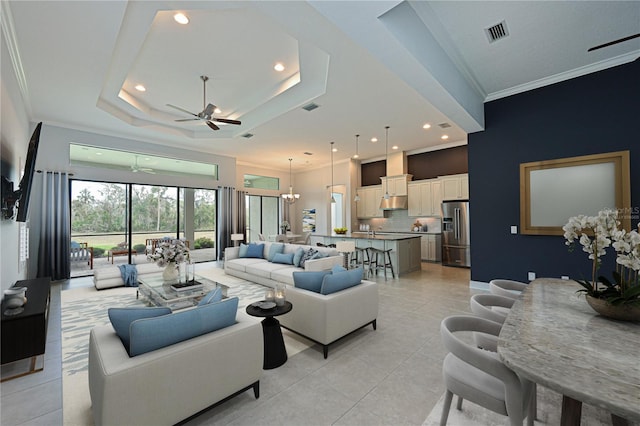 living room with crown molding, visible vents, a tray ceiling, and light tile patterned flooring