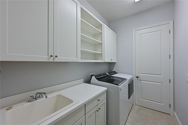 laundry area with washing machine and clothes dryer, light tile patterned floors, cabinet space, a sink, and a textured ceiling