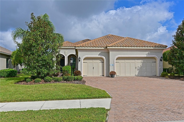 mediterranean / spanish-style house with a tiled roof, an attached garage, decorative driveway, a front lawn, and stucco siding