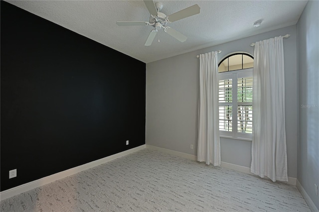 unfurnished room with light carpet, a ceiling fan, baseboards, and a textured ceiling