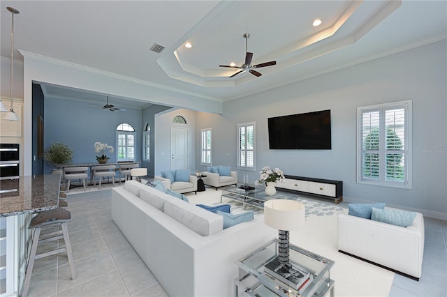 living area featuring a wealth of natural light, a tray ceiling, and visible vents